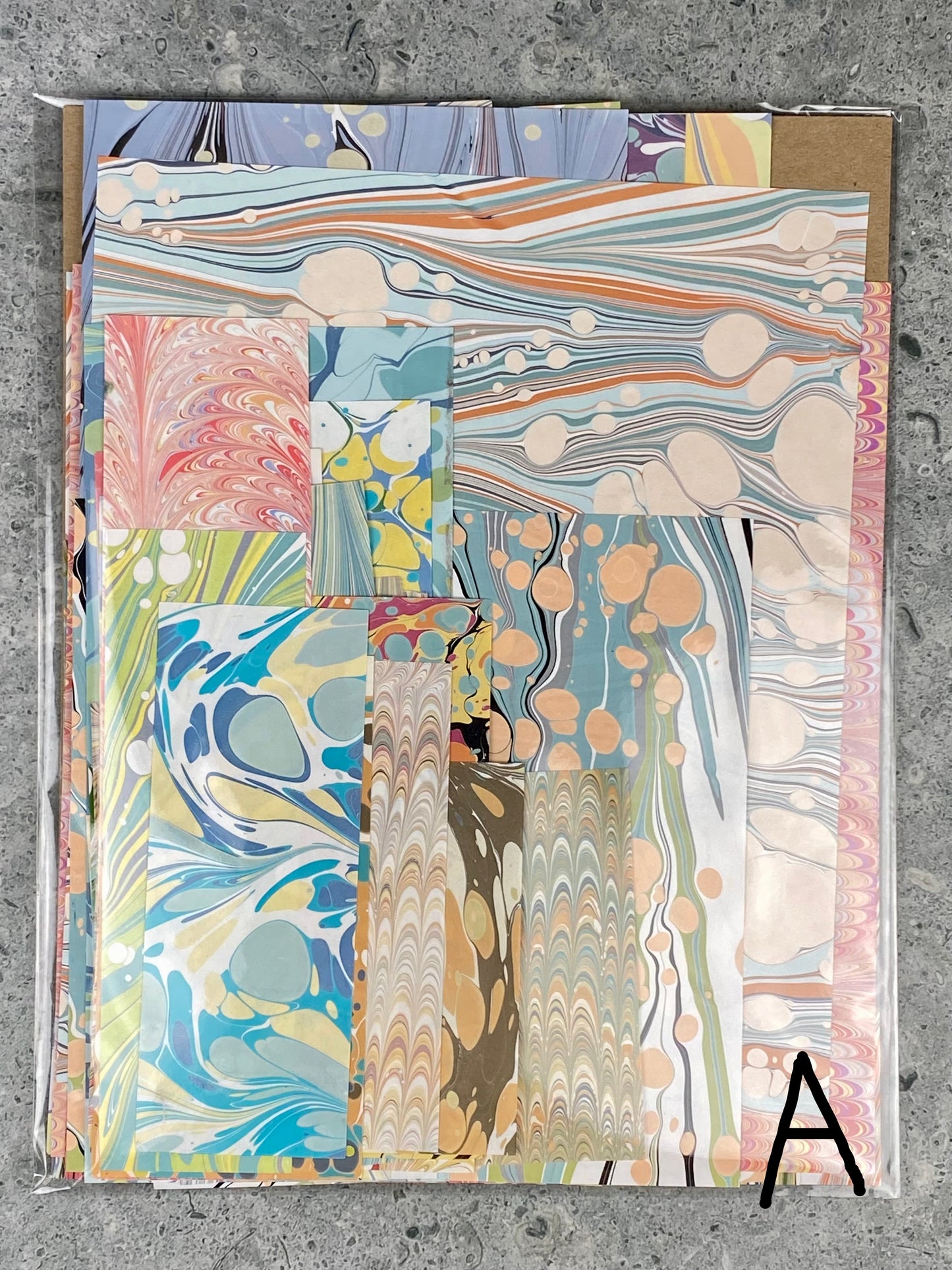 Set of marbled paper sheets with various patterns on a concrete surface