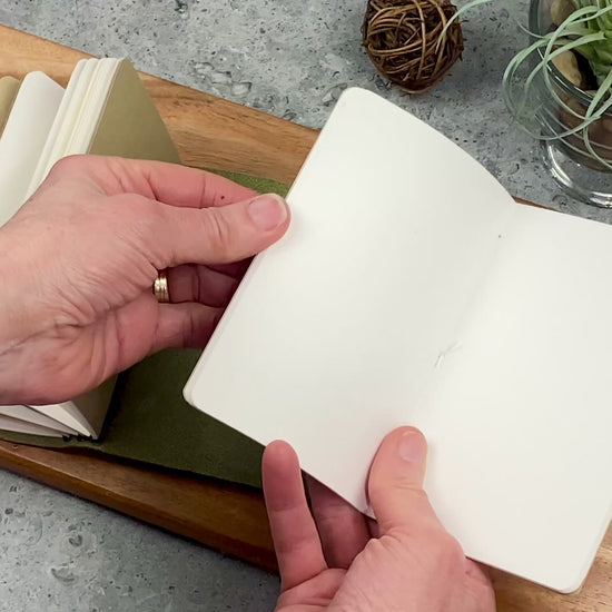 Pocket size refill booklet being inserted into a leather journal cover